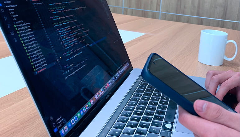 ノートパソコンの画面にコードエディタが表示され、プログラミング作業中の様子。